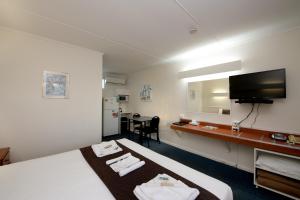 a hotel room with two beds and a television at Mineral Sands Motel in Maryborough