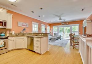 a kitchen with orange walls and white cabinets and a living room at Happy Hours in Carolina Beach