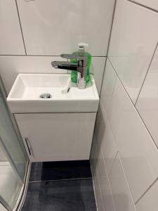 a white bathroom sink with a green faucet on it at Modern Studios Epsom Station in Epsom