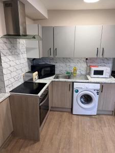a kitchen with a washing machine and a microwave at Modern Studios Epsom Station in Epsom