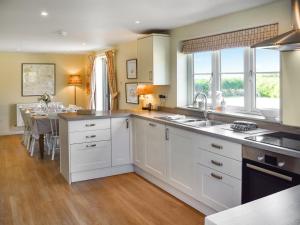 a kitchen with white cabinets and a dining room at Green Farm Cottage in Redgrave +18 photos