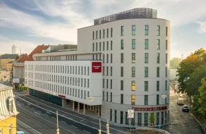 a tall white building on a city street at Leonardo Hotel Augsburg in Augsburg