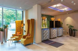 a waiting room with two chairs and a tv at Leonardo Hotel Augsburg in Augsburg