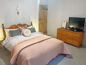 a bedroom with a bed and a tv on a dresser at John Wesley Cottage in Tantobie