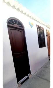 a white building with a black door and a window at Sunset bed in Puerto Chicama