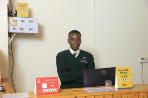 a man standing in front of a desk with a computer at Hakyiri B&B in Kabale