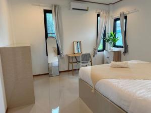 a bedroom with a bed and a desk and windows at Very Central Boho Home in Srithanu in Ko Kong Nui