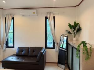 a living room with a leather couch and windows at Very Central Boho Home in Srithanu in Ko Kong Nui