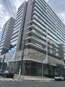 a tall building with cars parked in front of it at Edifício Catamara in Vila Velha