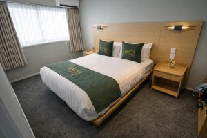 a bedroom with a large bed with green pillows at Rayya Suites, Paihia in Paihia