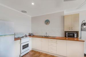 a kitchen with white cabinets and a sink and a microwave at 10T Beachfront Apartments in Lennox Head +10 photos