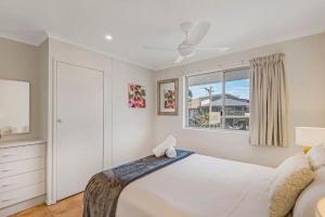 a white bedroom with a bed and a window at 10T Beachfront Apartments in Lennox Head
