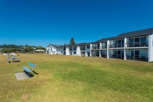 a building with a park with a bench in the grass at 10T Beachfront Apartments in Lennox Head