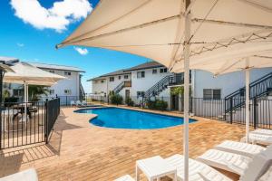 a swimming pool with umbrellas and chairs and a pool at 10T Beachfront Apartments in Lennox Head