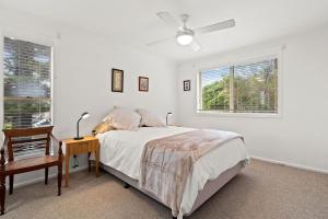 a bedroom with a bed and a desk and two windows at Shelly Vista in East Ballina