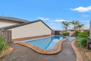 a swimming pool with a curved path around a house at Shelly Vista in East Ballina