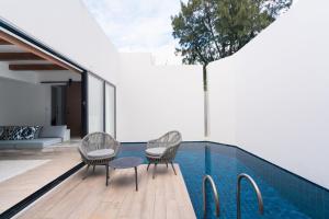 a swimming pool with two chairs and a table next to a house at Grand Bleu Gamin in Miyako-jima