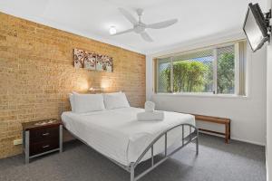 a bedroom with a bed and a brick wall at Ballina Golf Unit in East Ballina