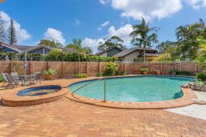 a swimming pool with a patio and a fence at Ballina Golf Unit in East Ballina