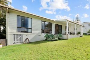 a white house with a lawn in front of it at Baileys Beach House in East Ballina