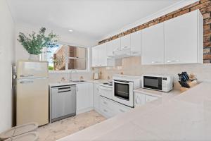 a kitchen with white appliances and a brick wall at Sun Soaked Lennox Village in Lennox Head