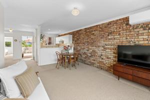 a living room with a brick wall at Sun Soaked Lennox Village in Lennox Head