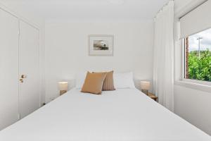 a white bedroom with a large bed and a window at Sun Soaked Lennox Village in Lennox Head