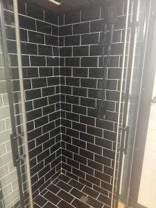 a shower with a black and white tiled wall at Rural Oasis - Tiny Home 2BR Cabin & Outdoor Firepit Experience in Palmwoods +9 photos
