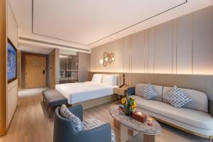 a hotel room with a bed and a couch at Orange Hotel Kunshan MixC Hotel in Kunshan