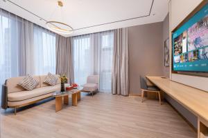 a living room with a couch and a flat screen tv at Orange Hotel Kunshan MixC Hotel in Kunshan