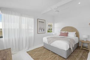 a white bedroom with a bed and a window at Walters in East Ballina