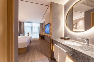 a bathroom with a sink and a bed and a mirror at Orange Hotel Kunshan MixC Hotel in Kunshan +35 photos