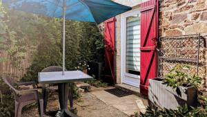 a table and chair with an umbrella on a patio at La parenthèse bucolique in Cheissoux
