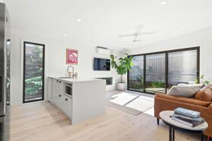 a white kitchen and living room with a couch at Blue Ash Studio in Lennox Head