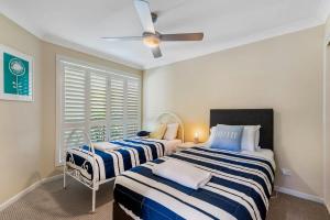 a bedroom with two beds and a ceiling fan at Frangipani Hideaway in Lennox Head