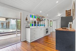 a kitchen with white cabinets and a large window at Hinterland Views in Lennox Head