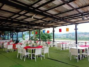 a restaurant with tables and white chairs and red tables at Chiangkhong Teak Garden Riverfront Hotel in Chiang Khong