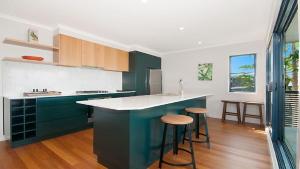 a kitchen with green cabinets and a counter with stools at KK s in Lennox Head in Lennox Head