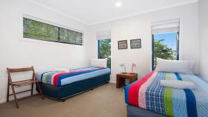 a bedroom with two beds and a chair at KK s in Lennox Head in Lennox Head