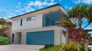 a white house with a blue garage door at KK s in Lennox Head in Lennox Head