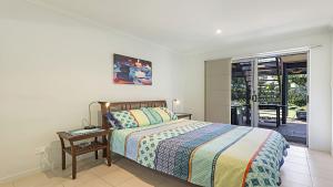 a bedroom with a bed and a table and a window at Moana Retreat in Lennox Head