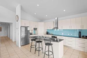 a kitchen with white cabinets and bar stools at Oceanic 3 in East Ballina