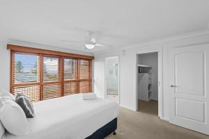 a white bedroom with a large bed and a window at Oceanic 3 in East Ballina