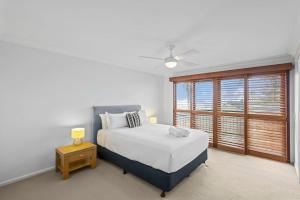 a white bedroom with a bed and a window at Oceanic 3 in East Ballina +8 photos
