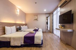 a hotel room with two beds and a television at Lavender Inn Nusa Bestari in Johor Bahru