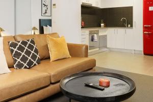 a living room with a brown couch and a table at Spacious Studio in a Prime Braddon Location - Hosted by Canstay in Braddon +17 photos