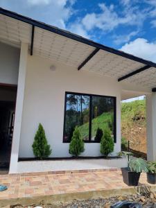 a white house with two potted plants on a patio at "Refugio campestre familiar - Cálido, cómodo y totalmente equipado" y zona de juegos in Nariño