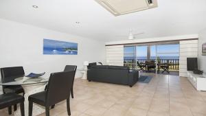 a living room with a table and chairs and a view of the ocean at Quarterdeck 23 in Lennox Head +4 photos