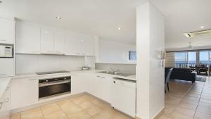 a kitchen with white cabinets and a dining room at Quarterdeck 23 in Lennox Head
