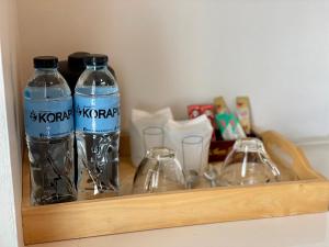two bottles of water and two glasses on a shelf at Korapura Resort in Nakhon Ratchasima